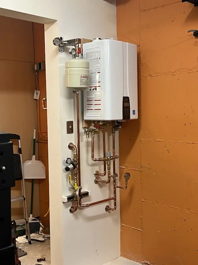 Plumbing technician inspecting water heater connections in Clawson